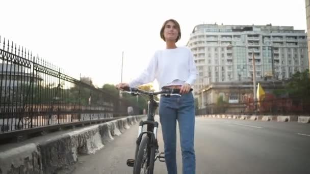 attractive female walks along the street carrying her bicycle - Кадри, відео