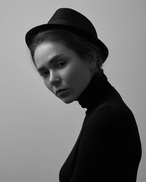 Drámai fekete-fehér portré fiatal gyönyörű lány, szeplő egy fekete garbó és egy kalap, egy fehér háttér-a stúdió - Fotó, kép