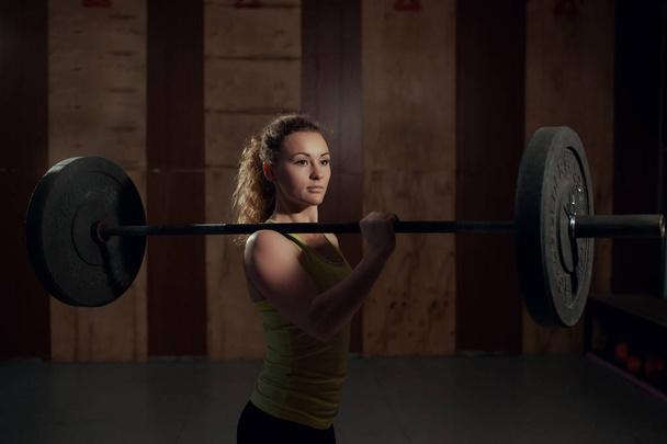 The athlete holds the barbell on one shoulder. - 写真・画像