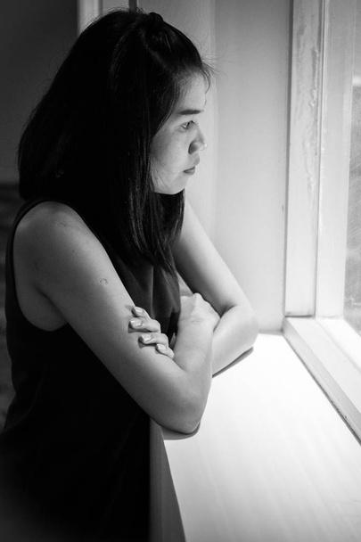 Smutna kobieta wyglądająca przez okno - Zdjęcie, obraz