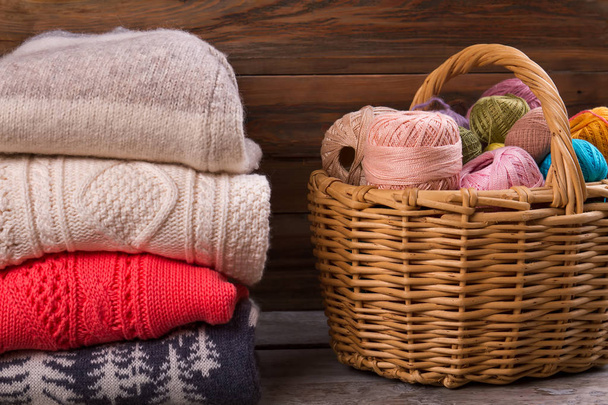 Stack of knitted sweaters on wooden background.  - 写真・画像