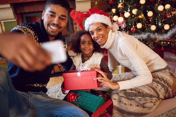 幸せな家族のクリスマス期間中にスマート フォンでセルフ ポートレートを撮影 - 写真・画像