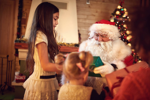 Santa Claus giving Christmas gifts to children - Foto, Imagen