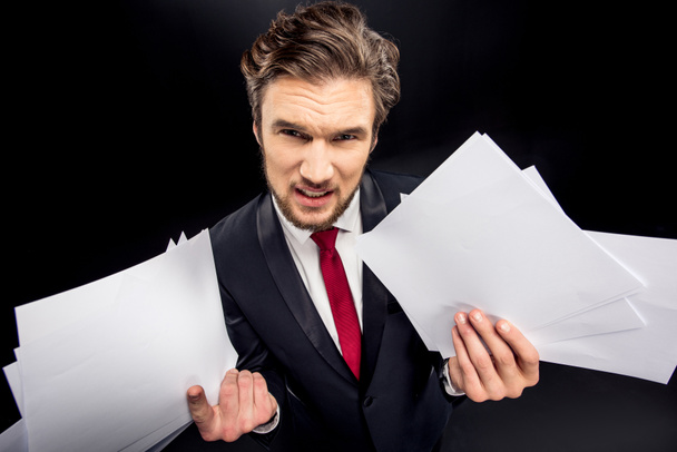 Annoyed businessman holding papers - Foto, afbeelding
