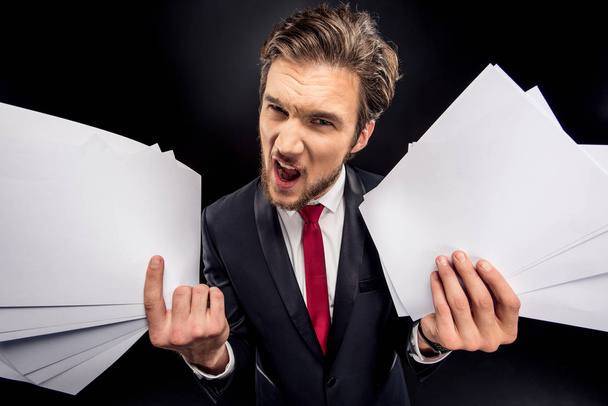 Annoyed businessman holding papers - Foto, afbeelding