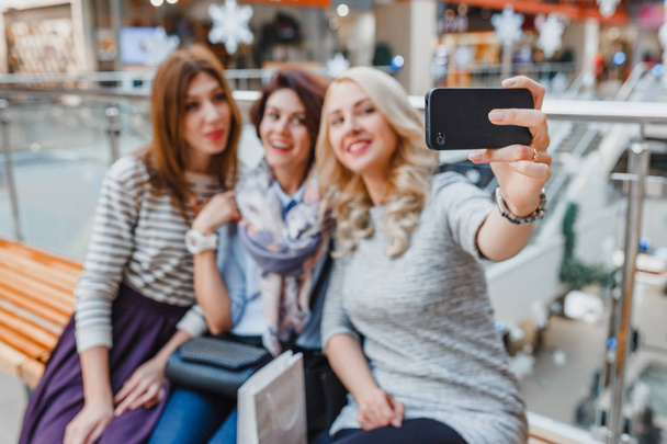 Tres mujeres novia tomar un descanso en las compras de Año Nuevo en el centro comercial y tomar selfie en el teléfono inteligente
 - Foto, imagen