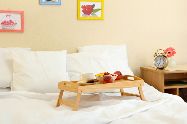 Wooden tray with light breakfast on bed - Fotoğraf, Görsel