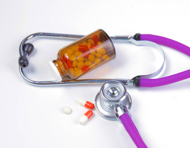 медицинский стетоскоп с таблетками изолированы на белом фоне
 - Фото, изображение