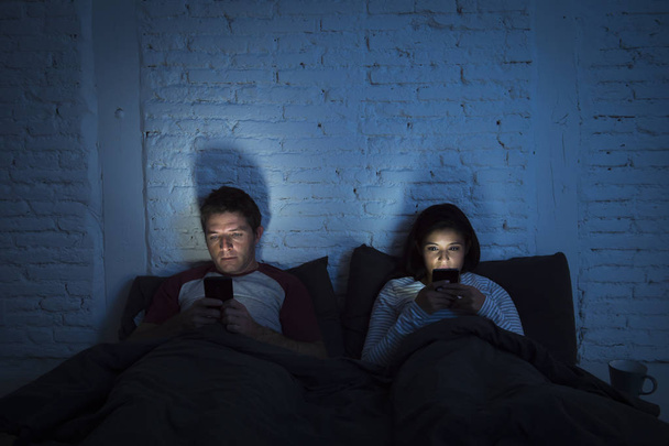 pár doma v posteli v noci pomocí mobilního telefonu v komunikaci problém vztahu - Fotografie, Obrázek