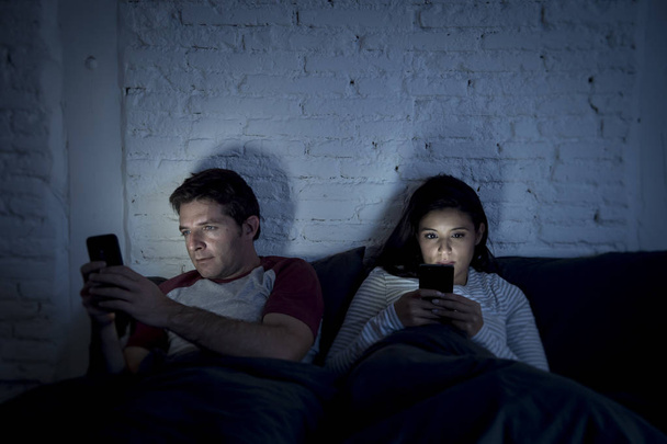 couple at home in bed late at night using mobile phone in relationship communication problem - Fotó, kép