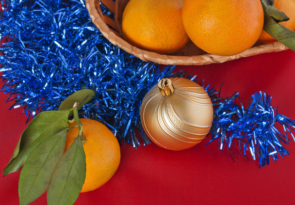 Basket with tangerines and yellow Christmas toys - Фото, изображение
