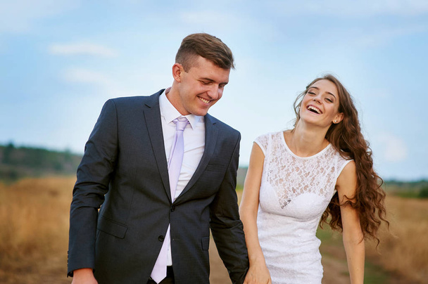 bride and groom walk in summer field - Valokuva, kuva