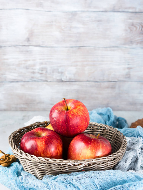 Fresh apples in basket on wooden background. Vertical - 写真・画像