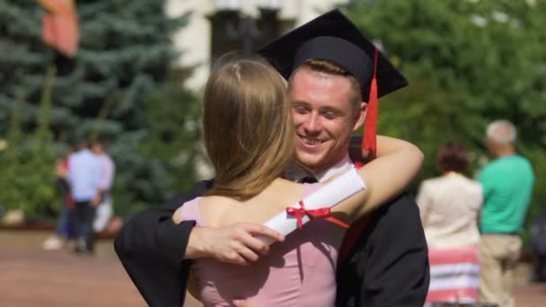 Beautiful woman congratulating boyfriend on graduation, happy couple hugging - Footage, Video
