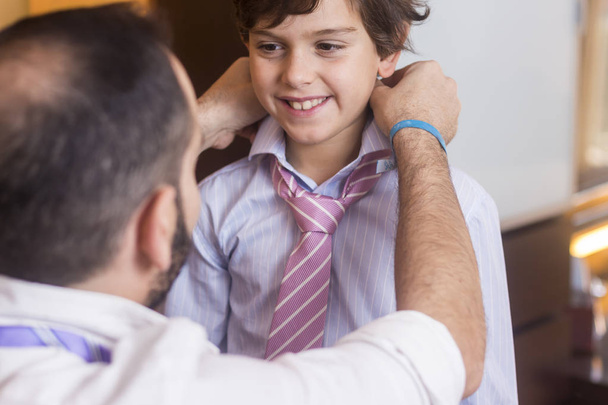 Father is helping his son to wear the tie. - Foto, Imagen