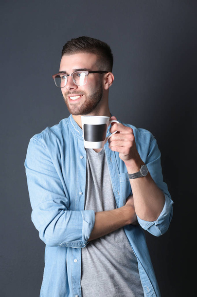 Portrait handsome young man standing and holding cup of coffee in his hands - Foto, Imagem