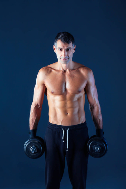 Handsome muscular man working out with dumbbells - Fotografie, Obrázek