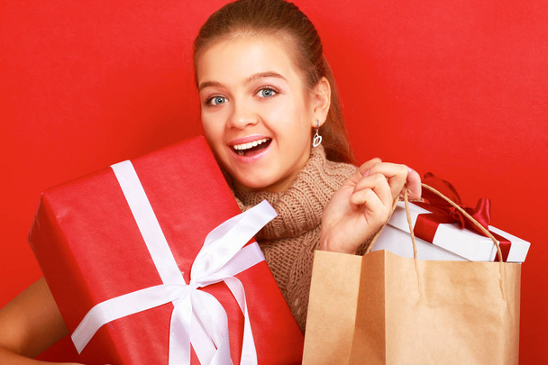 Young woman is standing while holding a bag of gifts over her shoulder - Foto, Imagem