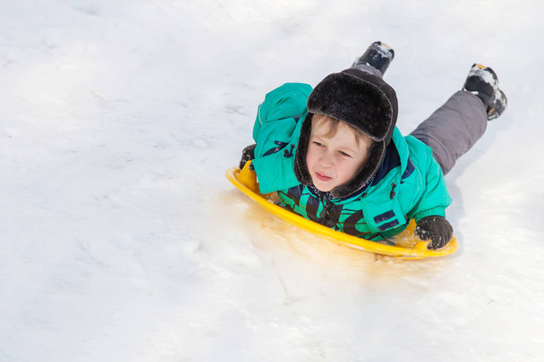 Niño deslizándose en platillo de nieve
 - Foto, Imagen