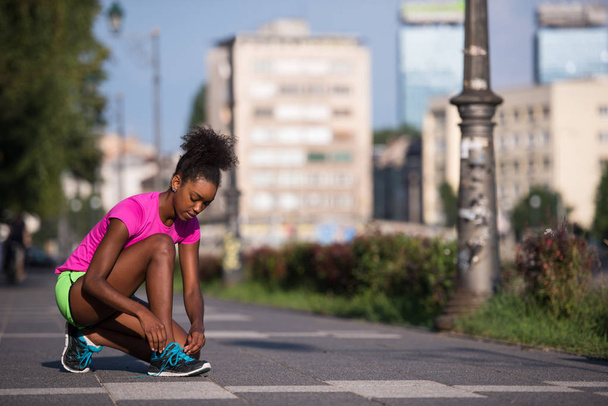 African american woman runner tightening shoe lace - Fotó, kép