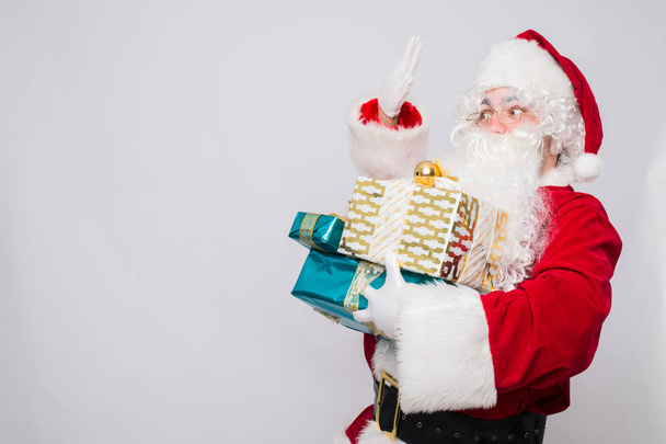 Portrait of Cheerful Santa Claus holding Christmas presents against white background - Photo, Image