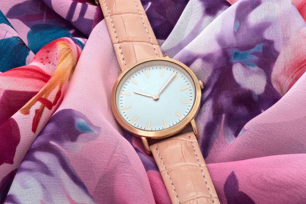 Pink wrist watch on colourful silk fabric background - Photo, Image