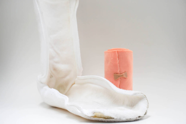 fechar a tala de perna branca isolada com rolo de bandagem em fundo branco
 - Foto, Imagem