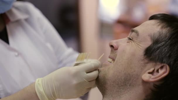 Close-up of young man in dentist chair, check and select the color of the teeth. - Filmmaterial, Video