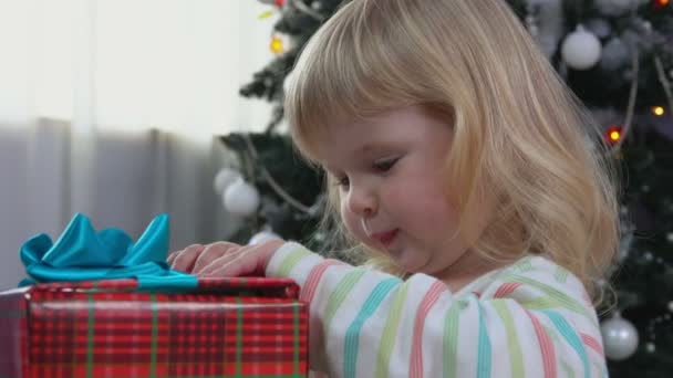 Little girl opens new years gift - Imágenes, Vídeo