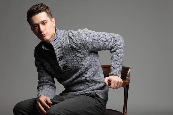 Sexy young man in warm knit sweateron a gray background . Male model.  - Фото, зображення