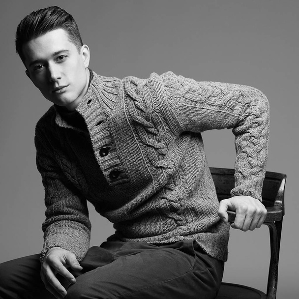 Sexy young man in warm knit sweateron a gray background . Male model.  - 写真・画像
