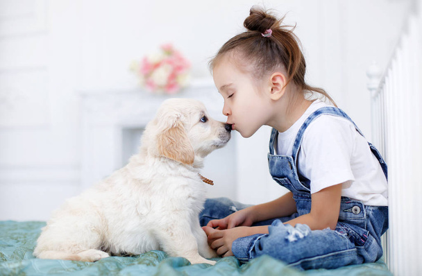 Little girl playing with a Puppy Retriever - Foto, imagen