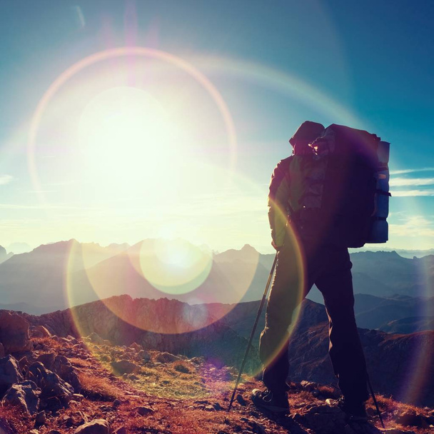 Lens flare defect.  Tourist guide on trekking path  with poles and backpack.  Experienced hiker - Фото, изображение
