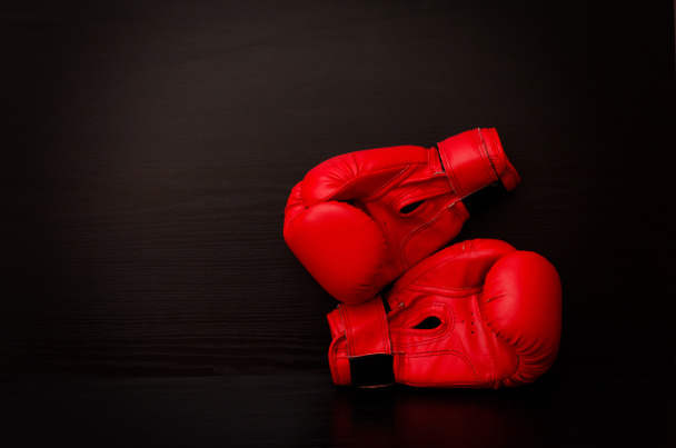 Red boxing gloves on a black background in the corner of the frame, place for text - Foto, Bild