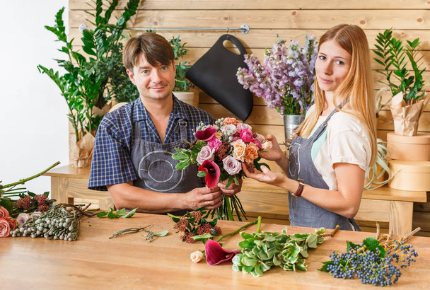 Квітник і помічник в квітковому магазині роблять трояндовий букет
 - Фото, зображення