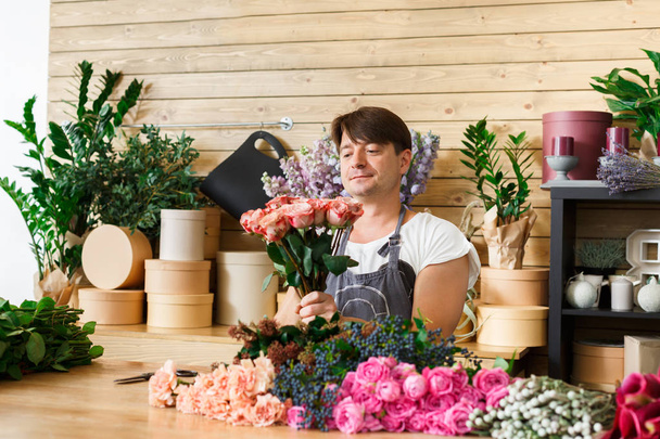 Man florist assistant in flower shop delivery make rose bouquet - 写真・画像