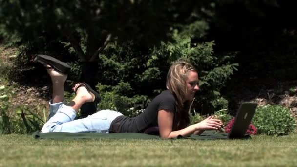 Eine junge Frau benutzt ihren Laptop draußen im Park - Filmmaterial, Video