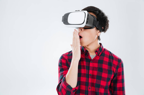 Surprised asian man dressed wearing virtual reality device - Foto, imagen