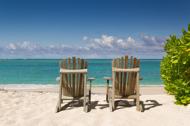 rustend stoelen op het mooie zandstrand in de buurt van de zee - Foto, afbeelding