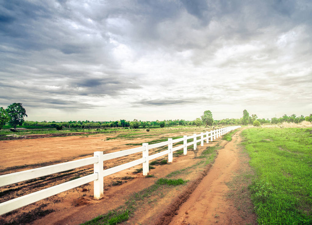witte hek in boerderij veld en bewolkte hemel - Zdjęcie, obraz