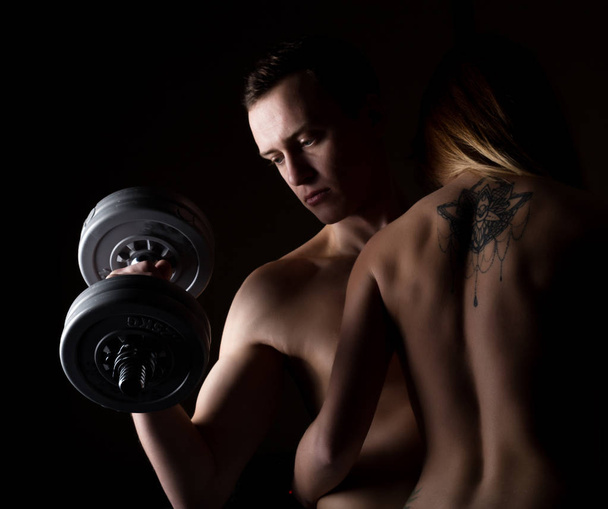 beautiful young sporty sexy couple showing muscle on a dark background - Foto, immagini