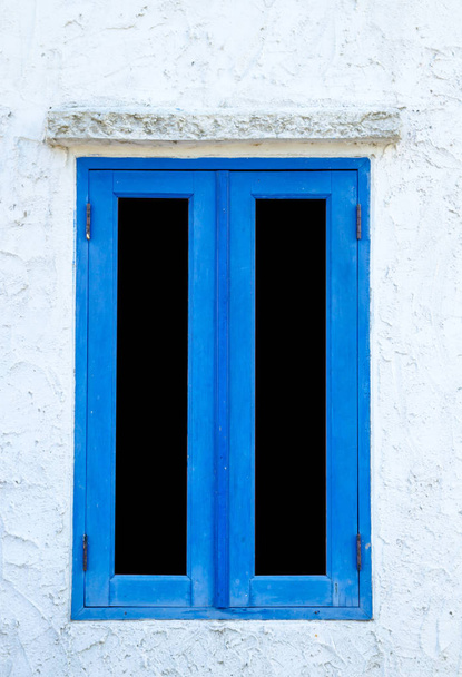 Okna z okiennicami w kolorze niebieskim na białej ścianie. - Zdjęcie, obraz