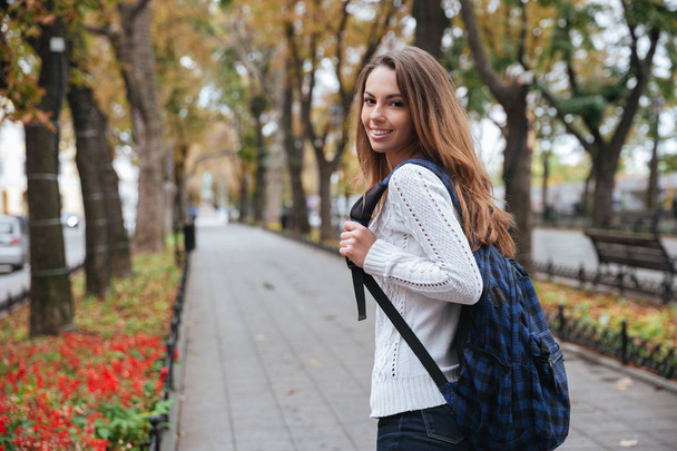 Cheerful attractive young woman with backpack walking in park - Φωτογραφία, εικόνα