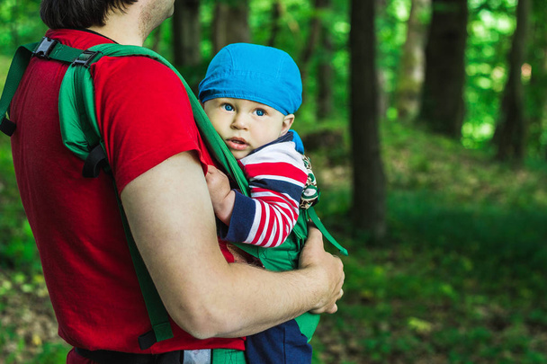 Père tenant son fils dans un porte-bébé marchant dans le parc
 - Photo, image