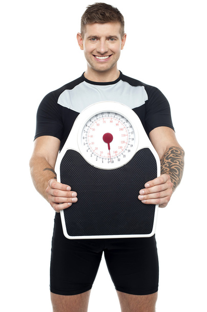Smart young fit male showing weighing machine - Photo, image