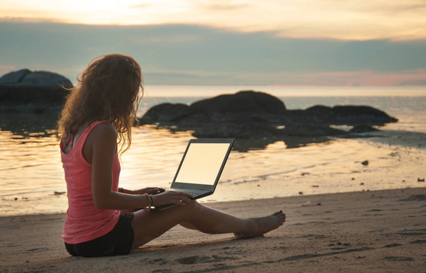 夕暮れのビーチはノート パソコンで女性フリーランサー - 写真・画像