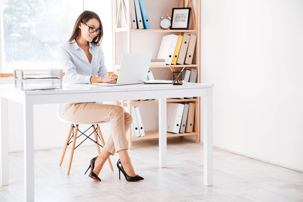 Businesswoman using laptop in office - 写真・画像