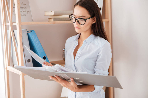 Young concentrated businesswoman holding folder - Photo, Image