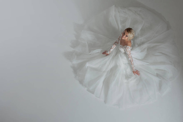 Beautiful bride in luxurious wedding dress, skirt lying around, the shape of a circle. White background, top view - Valokuva, kuva
