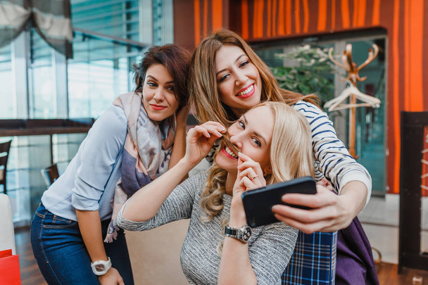 Three Happy cute girl friends Taking Selfie In Cafe. The concept of modern friendship and relations between women - Photo, Image